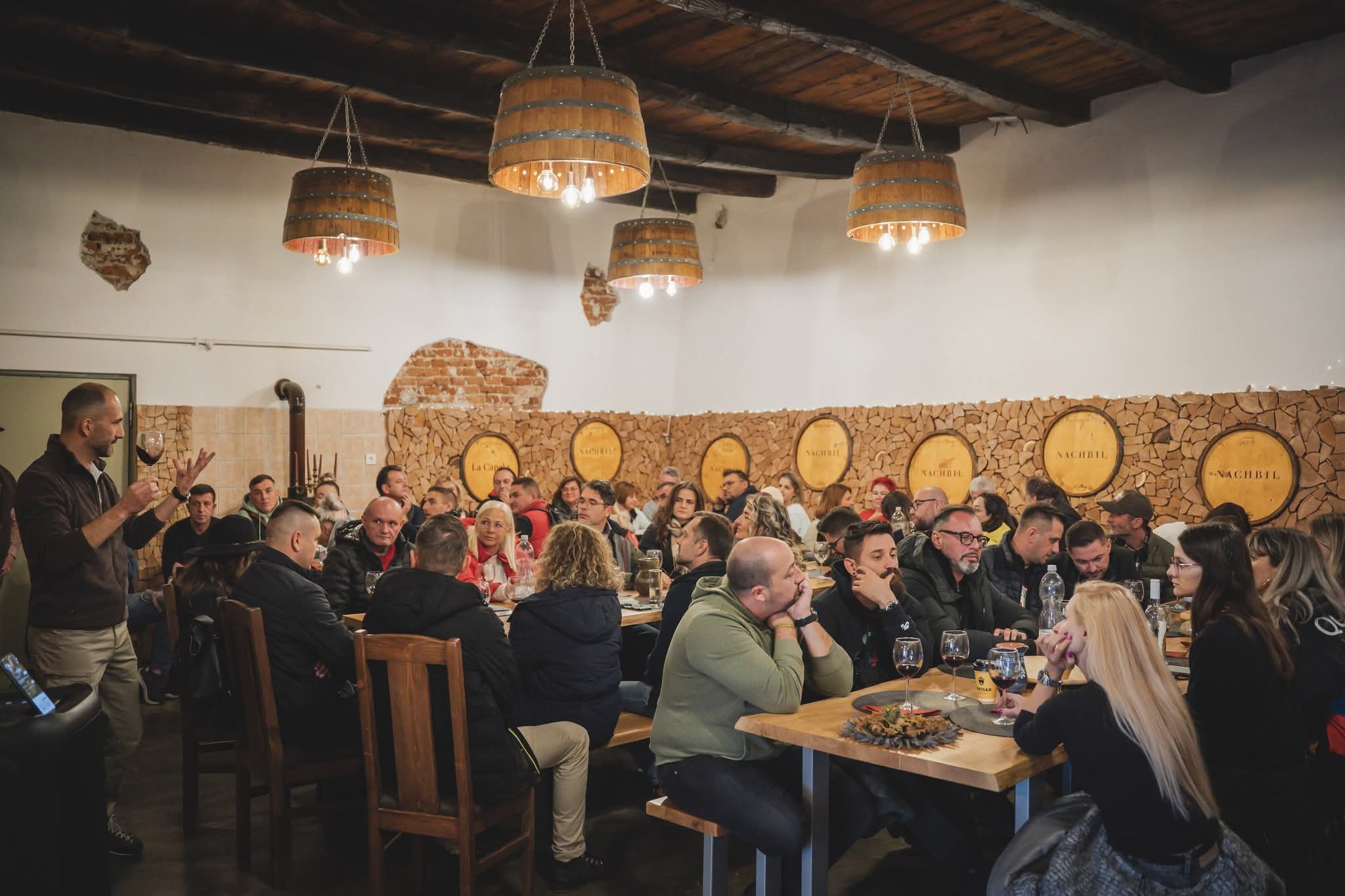 Participanți la o degustare în sala cu butoaie