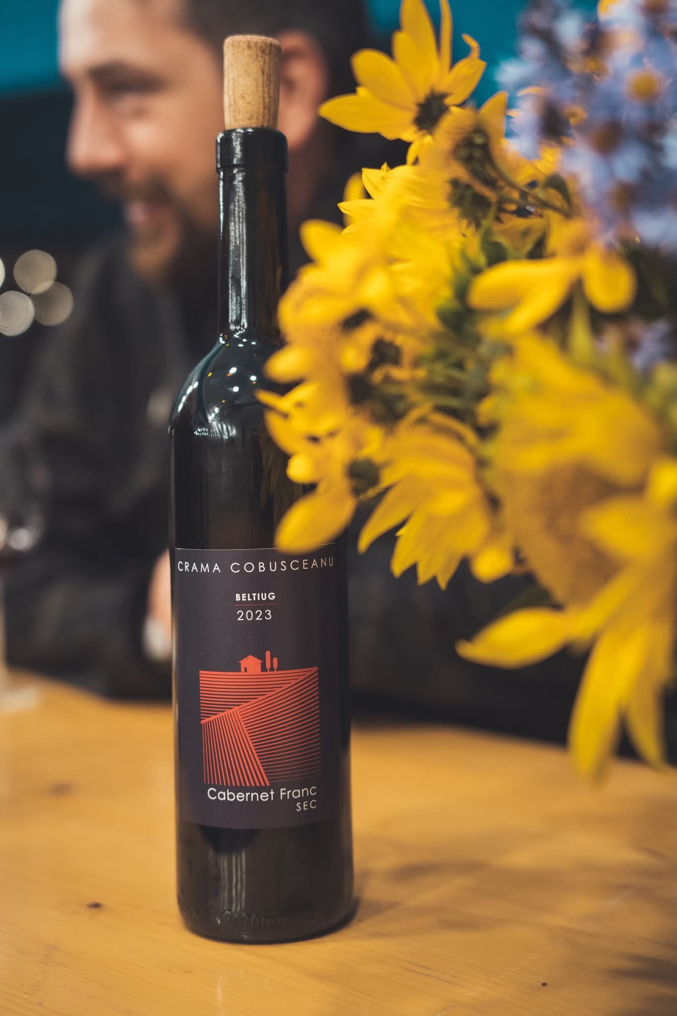 Sticlă de vin alături de flori de floarea-soarelui